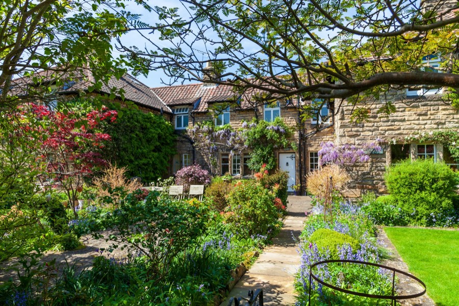 A cottage garden in full flower with a stone path to the house
