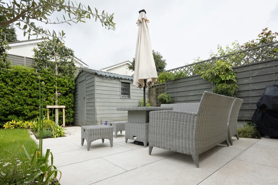 A small back garden with a new patio, painted shed and planting